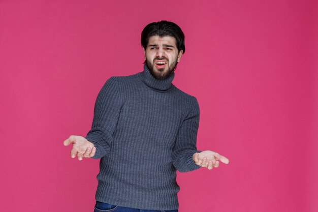 L'uomo con i capelli lunghi e la barba apre le mani e sembra confuso o inesperto.