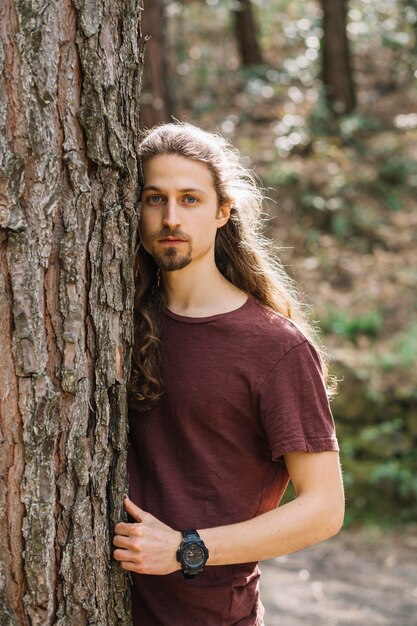 Man with long hair hugging a tree
