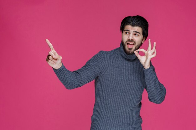 Man with long hairs and beard making zero circle sign in hand .