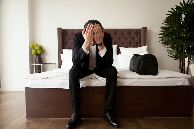 Man with luggage grieves at hotel after divorce