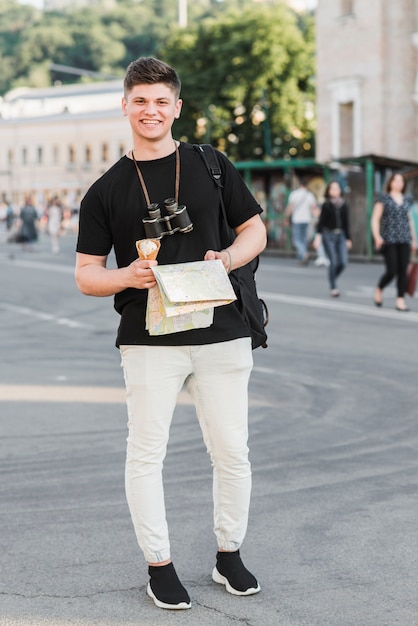 Бесплатное фото Человек с картой и рюкзаком, стоящим на улице