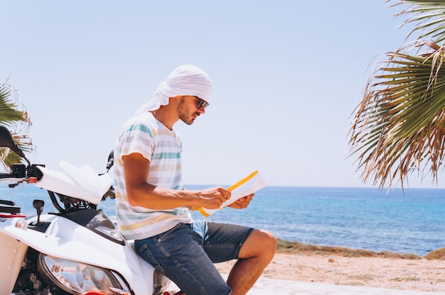 Man with map travalling on atv by the sea