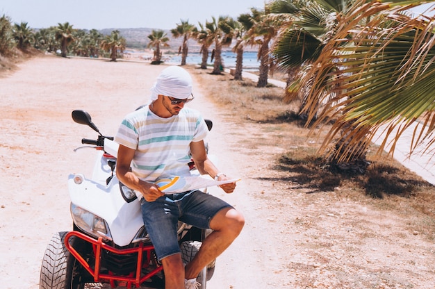 Man with map travalling on atv by the sea