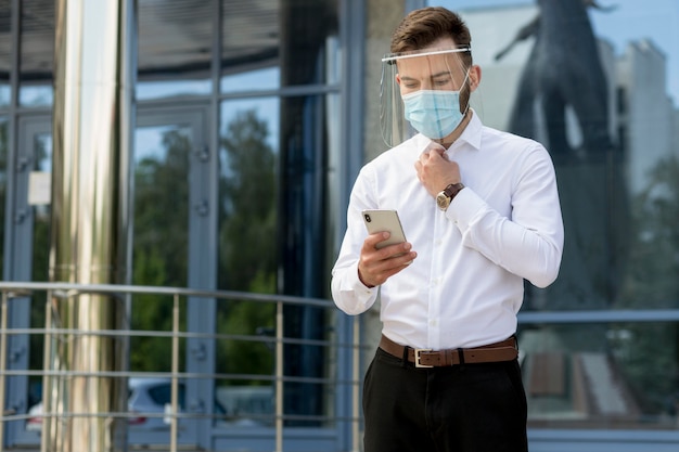 Foto gratuita uomo con maschera utilizzando il cellulare