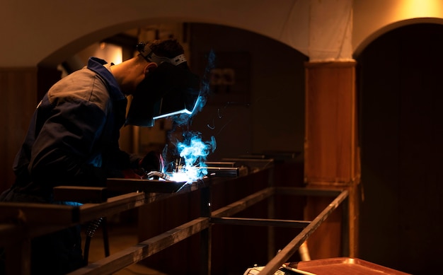 Free photo man with mask welding metal in the atelier