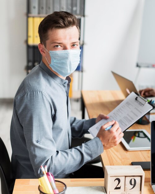Человек с маской, работающий в офисе во время пандемии