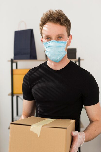 Человек с медицинской маской, держащей коробку
