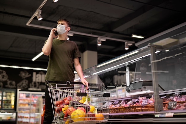 Uomo con maschera medica che fa la spesa al supermercato