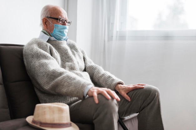 Бесплатное фото Человек с медицинской маской сидит в доме престарелых