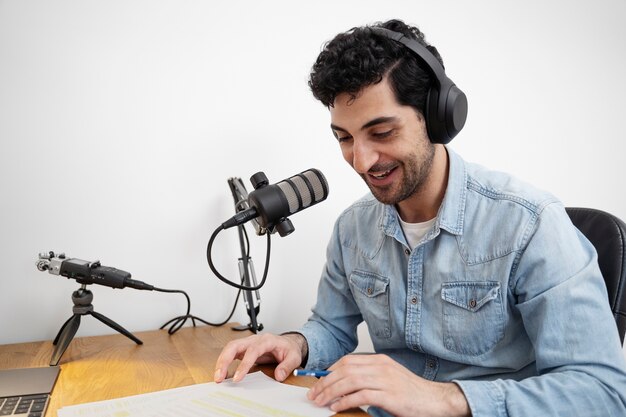 man with microphone running a podcast in the studio and reading from papers