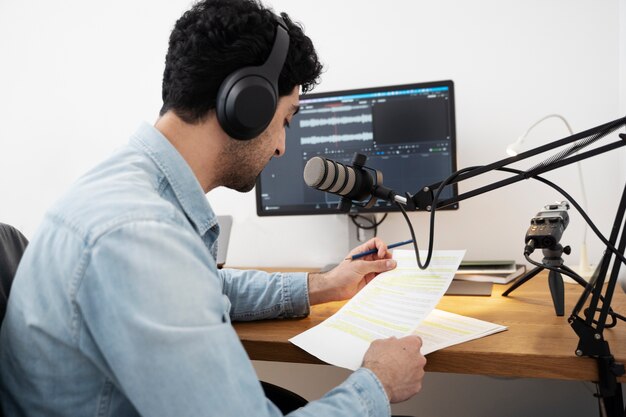 Man with microphone running a podcast in the studio and reading from papers