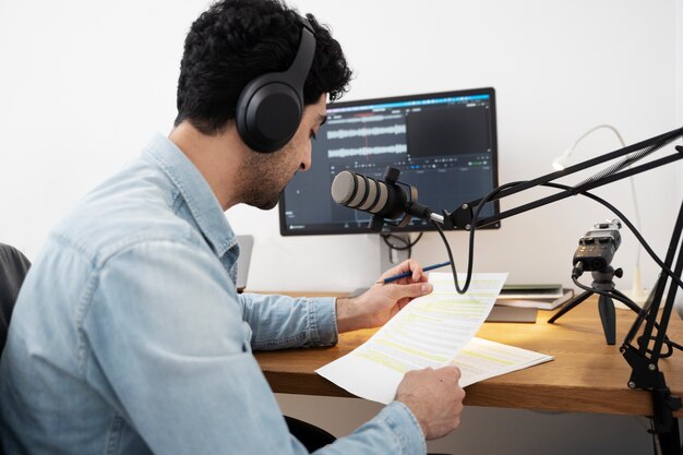 man with microphone running a podcast in the studio and reading from papers