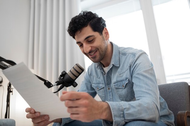 Man with microphone running a podcast in the studio and reading from papers