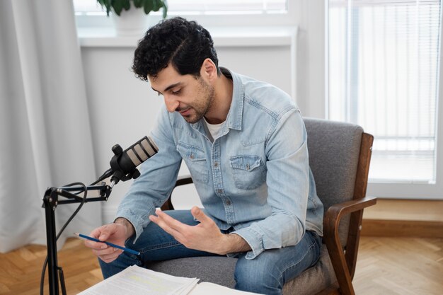 Man with microphone running a podcast in the studio and reading from papers