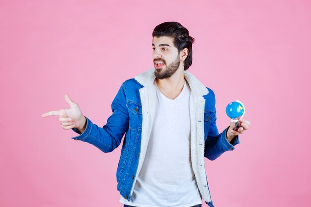Man with a mini globe pointing at someone
