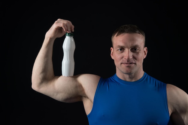 Man with muscular body and biceps hold yoghurt bottle with healthy drink, dieting and fitness, sport
