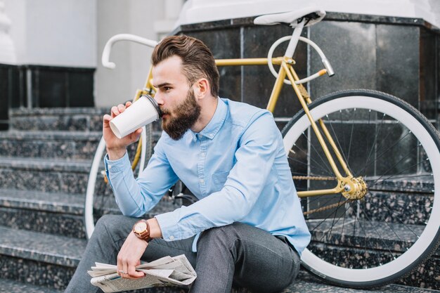 Man with newspaper drinking hot beverage