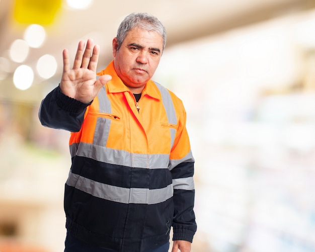 Man with an orange work jumpsuit making a "stop"