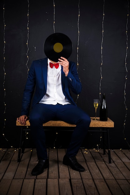 Man with phonograph disk near bottle and glass