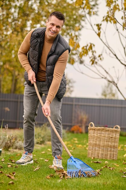 Man with rake cleaning leaves looking at camera