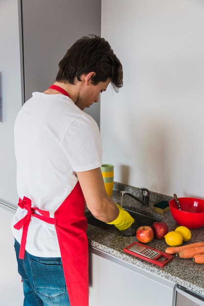 キッチンで働く赤いエプロンの男