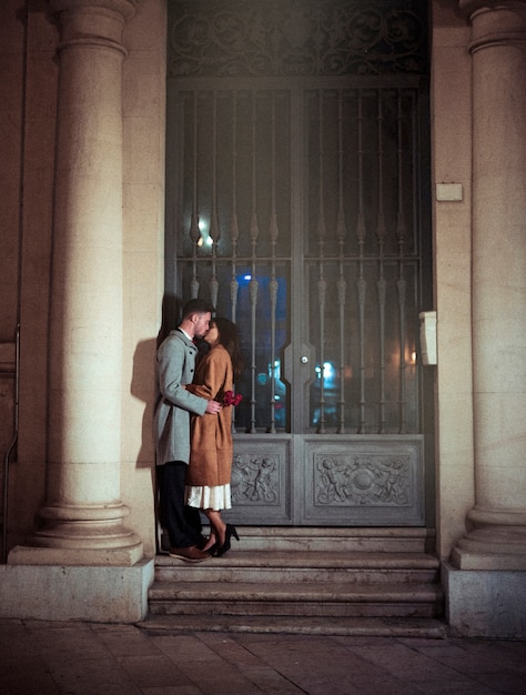 Man with red flowers kissing woman on lips