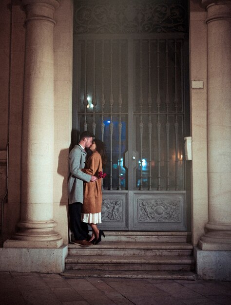 Man with red flowers kissing woman on lips