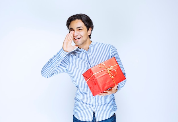 Man with a red gift box shouting for attention. High quality photo