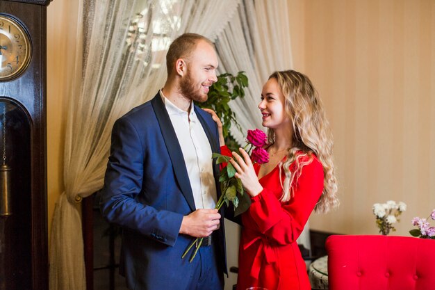 Man with roses hugging woman in restaurant 