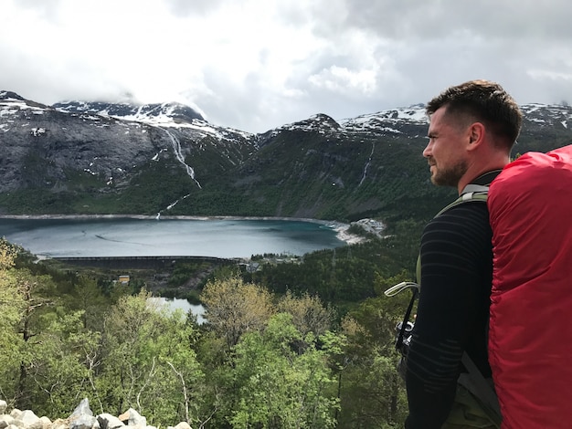 Free photo man with a rucksack admires gorgeous mountain landscape