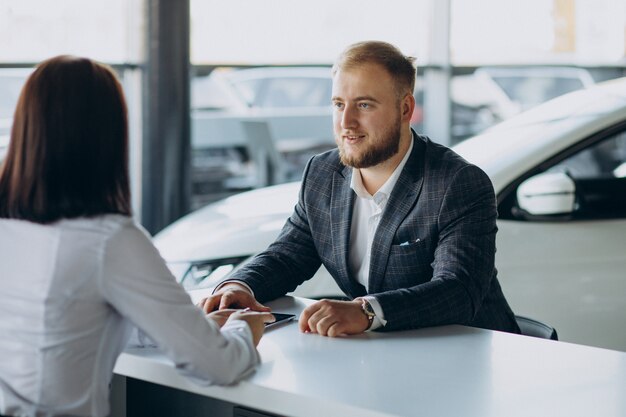 Man with sales woman in car showroom