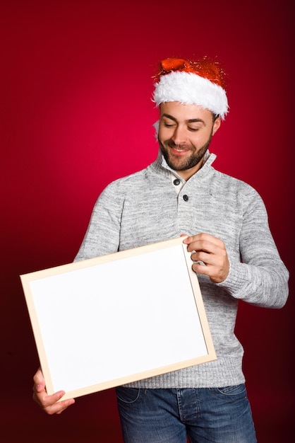 Man with santa hat holding blank board