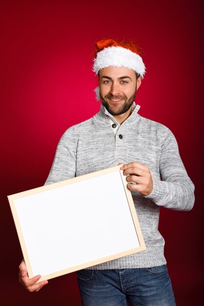空白のボードを保持サンタの帽子を持つ男