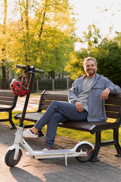 ベンチに座っているスクーターを持つ男