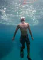 Foto gratuita uomo con attrezzatura subacquea nuotare nell'oceano