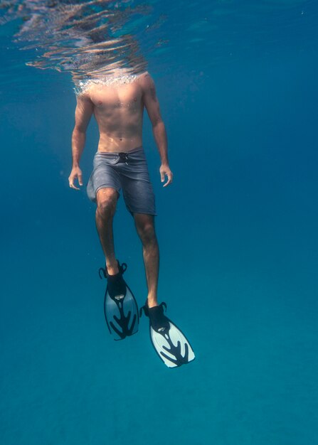 Foto gratuita uomo con attrezzatura subacquea nuotare nell'oceano