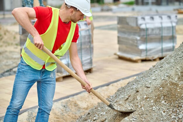 Man with shovel picking up rubble at construction site