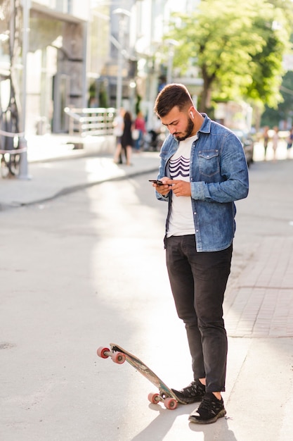 휴대 전화를 사용 하여 스케이트 보드를 가진 남자