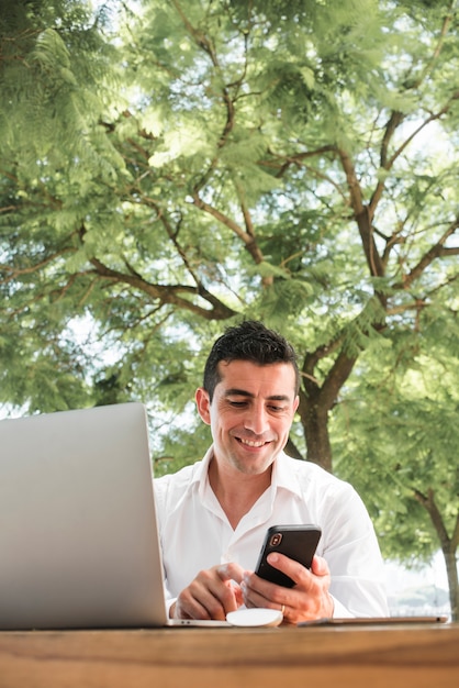 Man with smartphone and laptop outdoors