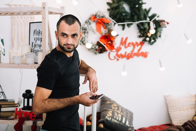 Man with smartphone near bed 