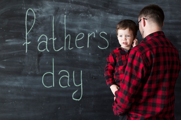 Free photo man with son on fathers day in front of chalkboard