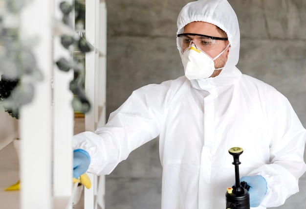 Free photo man with suit disinfecting shelf