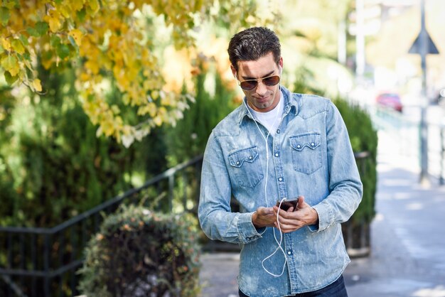 L'uomo con gli occhiali da sole a piedi e guardando il suo cellulare