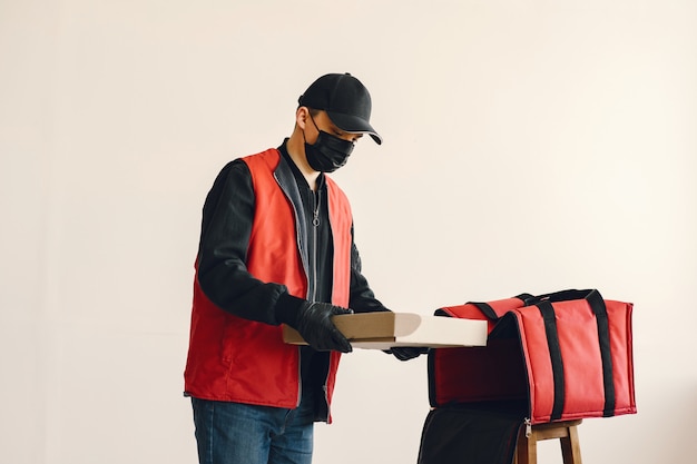 Man with surgical medical mask in uniform holding boxes