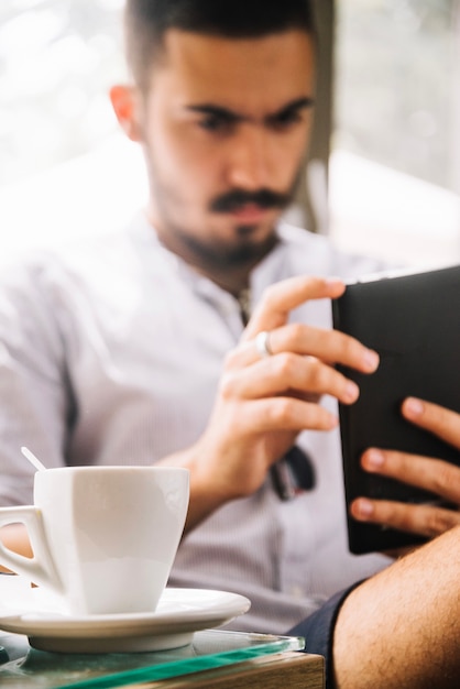 タブレットとコーヒーを持つ男