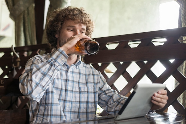 Foto gratuita uomo con tavoletta che beve birra