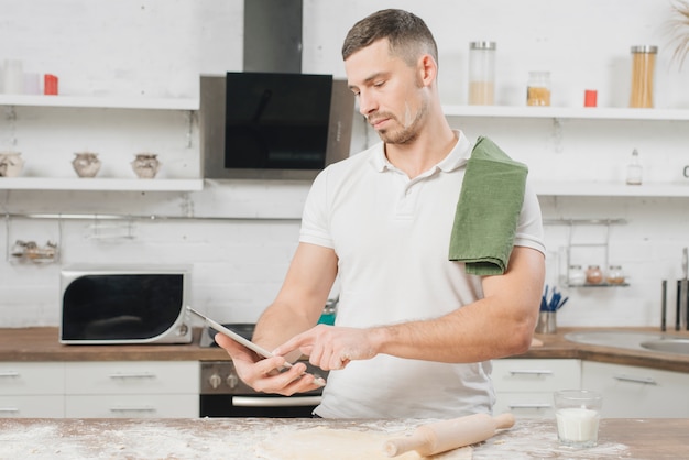 Foto gratuita uomo con tavoletta in cucina