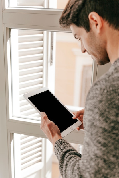 Man with tablet near window