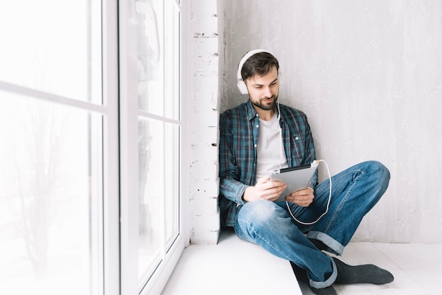 Man with tablet relaxing near window