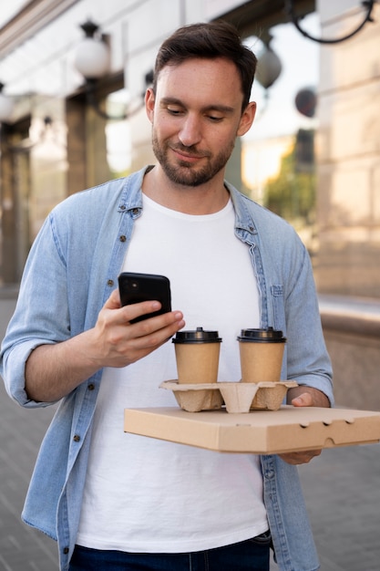 Man with takeaway food on the street using smartphone